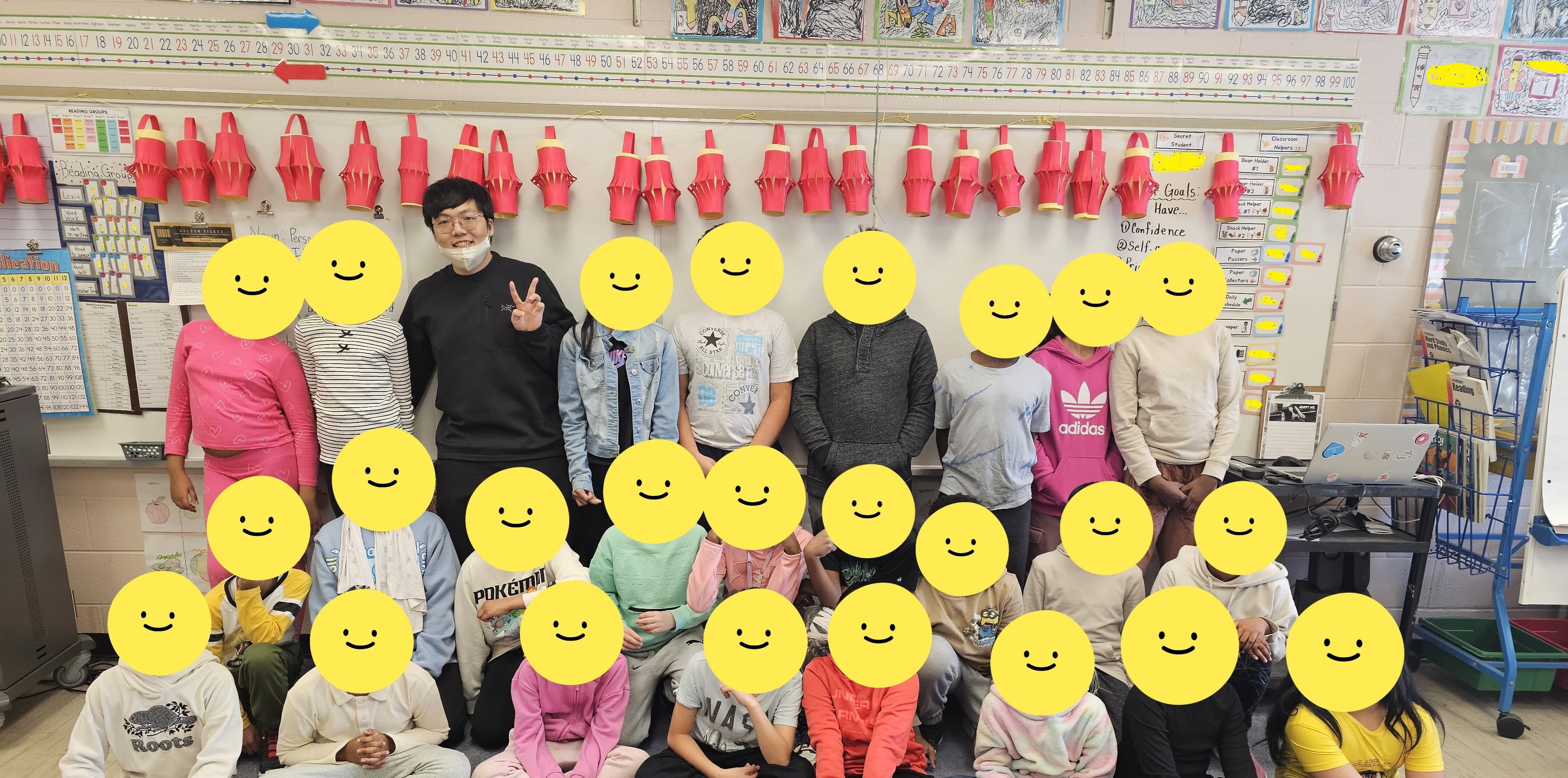 Hyun Kyoon Joo standing with the Grade 4/5 class at Highview Public School. Student faces are covered.