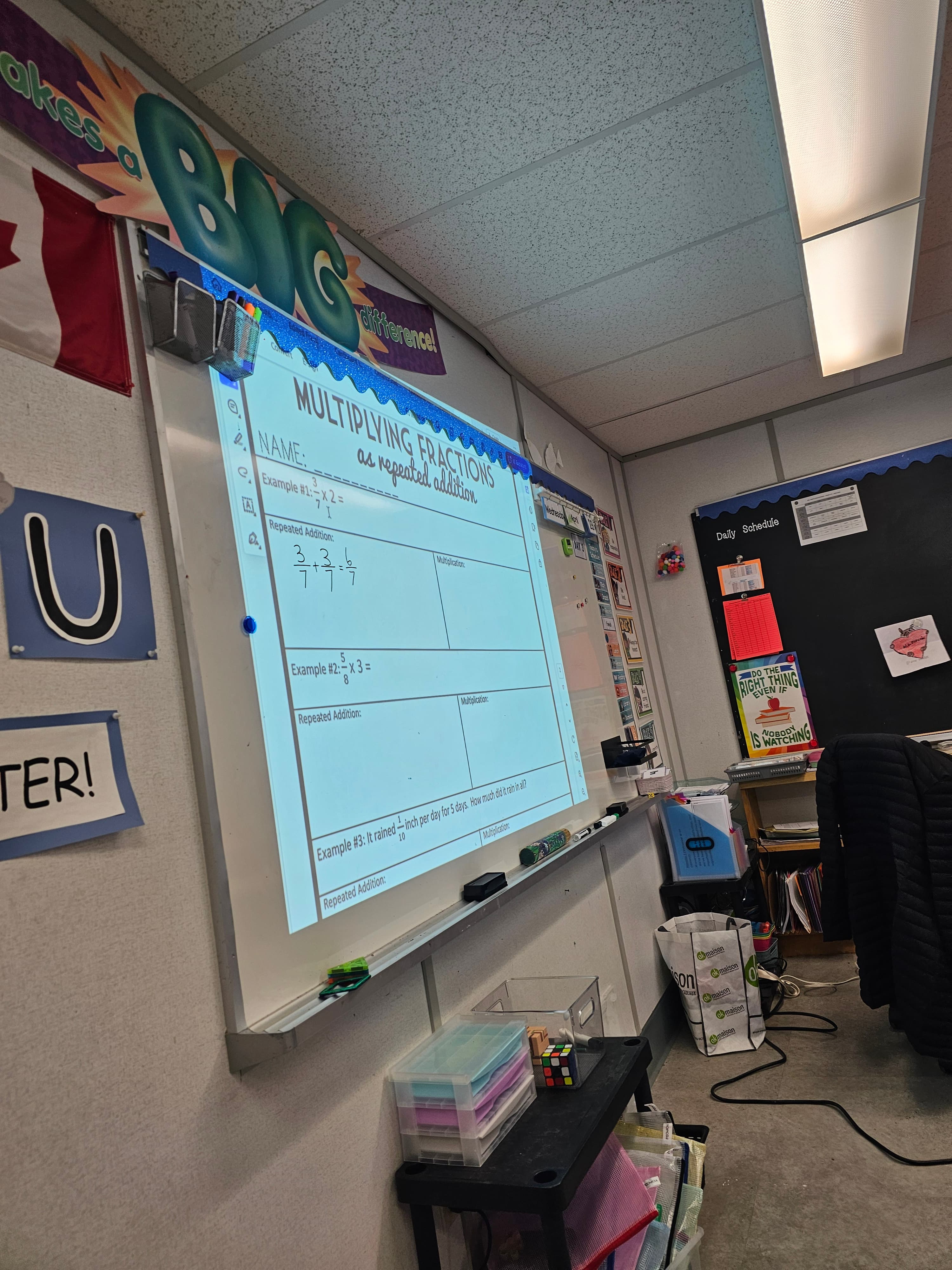 Mathematics lesson on multiplying fractions projected on a classroom whiteboard at Blue Willow Public School